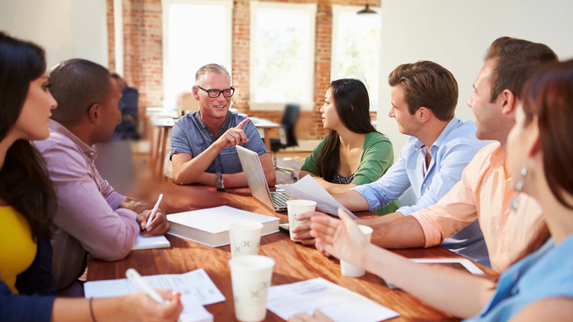 Diverse business team collaborating during a meeting around a table in a modern office.